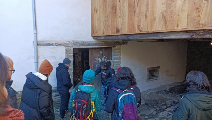 Uxío Novo, en Parada do Courel, amosa ao grupo unha porta de madeira que dá acceso a unha estancia. Nela pódese ler "chove para que eu soñe"